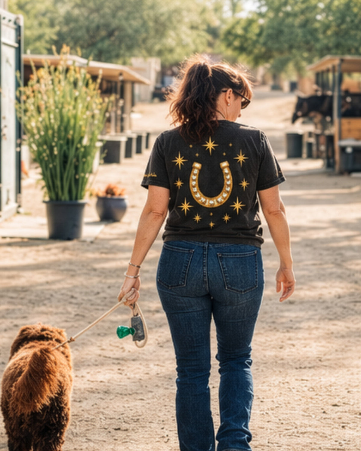 Icon Tee in black, back, worn walking through the barn yard with a dog.