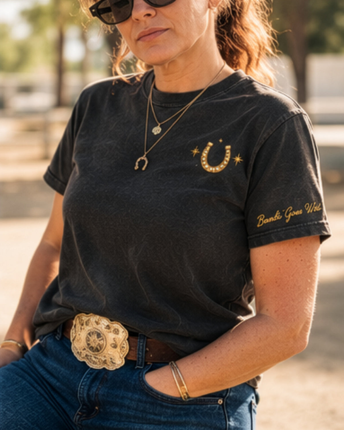Icon Tee in black, front: a small gold horseshoe with a star on each side at the left chest, and script on the sleeve.